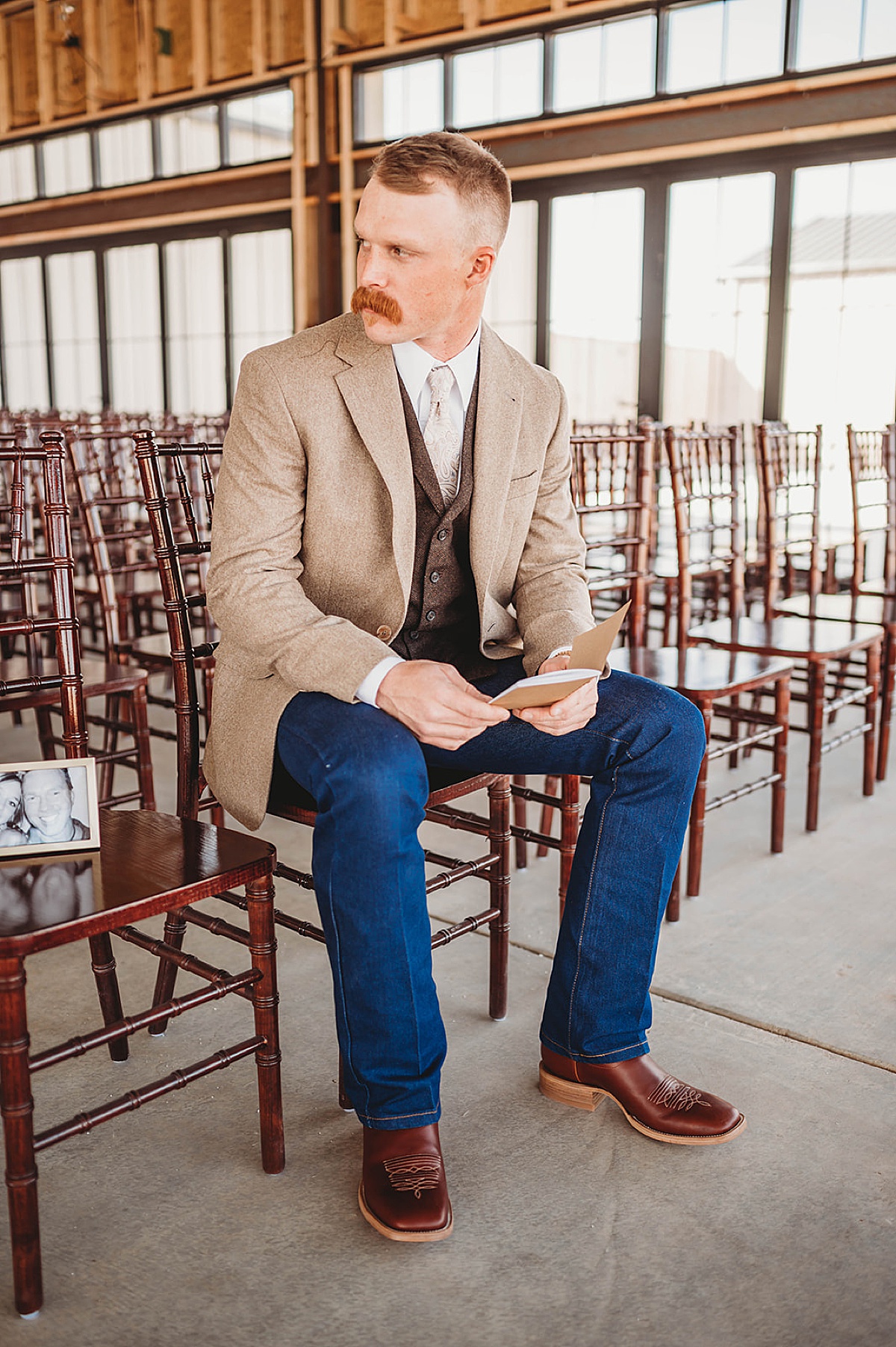 Groom contemplates bride's vows while getting ready for boho prairie wedding