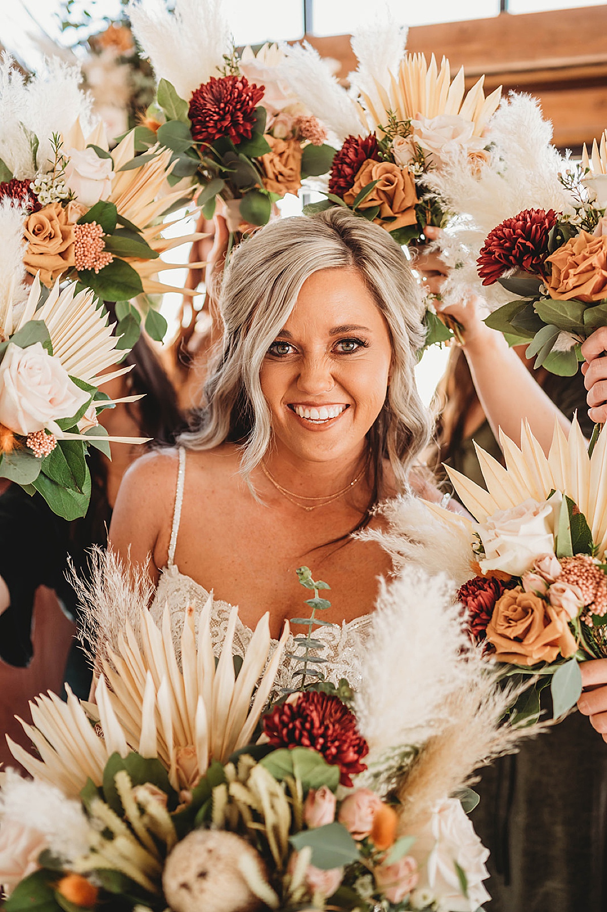 Bride poses surrounded by bridesmaids' boho dried flower bouquets in wedding shot by Three Feather Photography in Amarillo