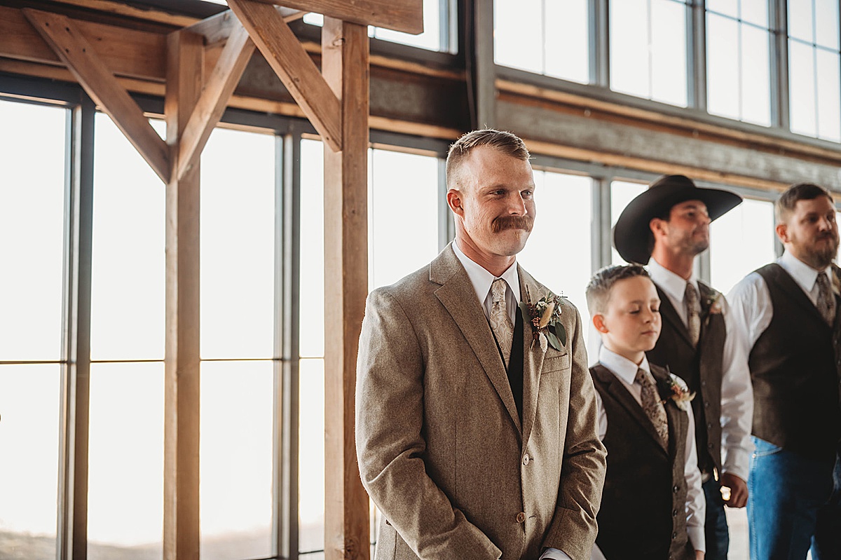Groom smiles as bride walks the aisle at wedding ceremony shot by Three Feathers Photography in Amarillo