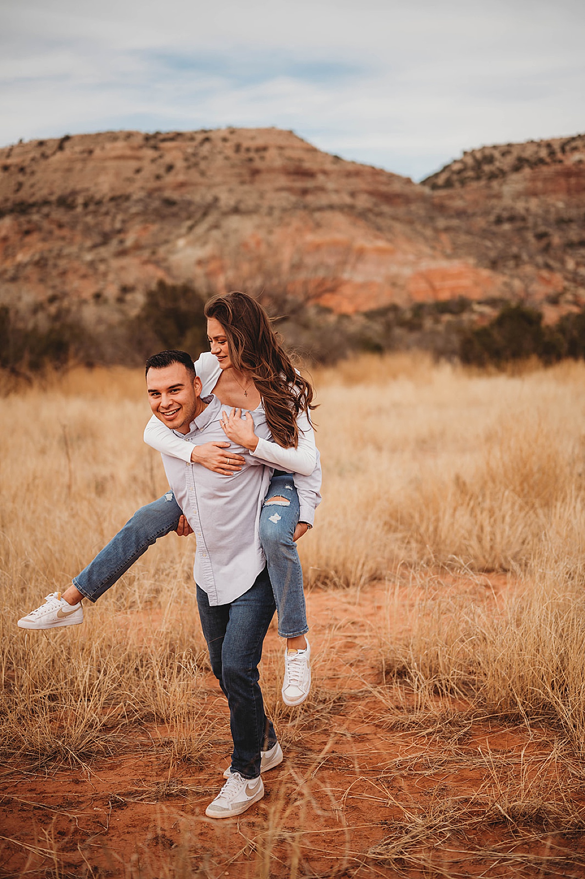 fiance gives his girl a piggy back ride during cute canyon adventure engagement shoot