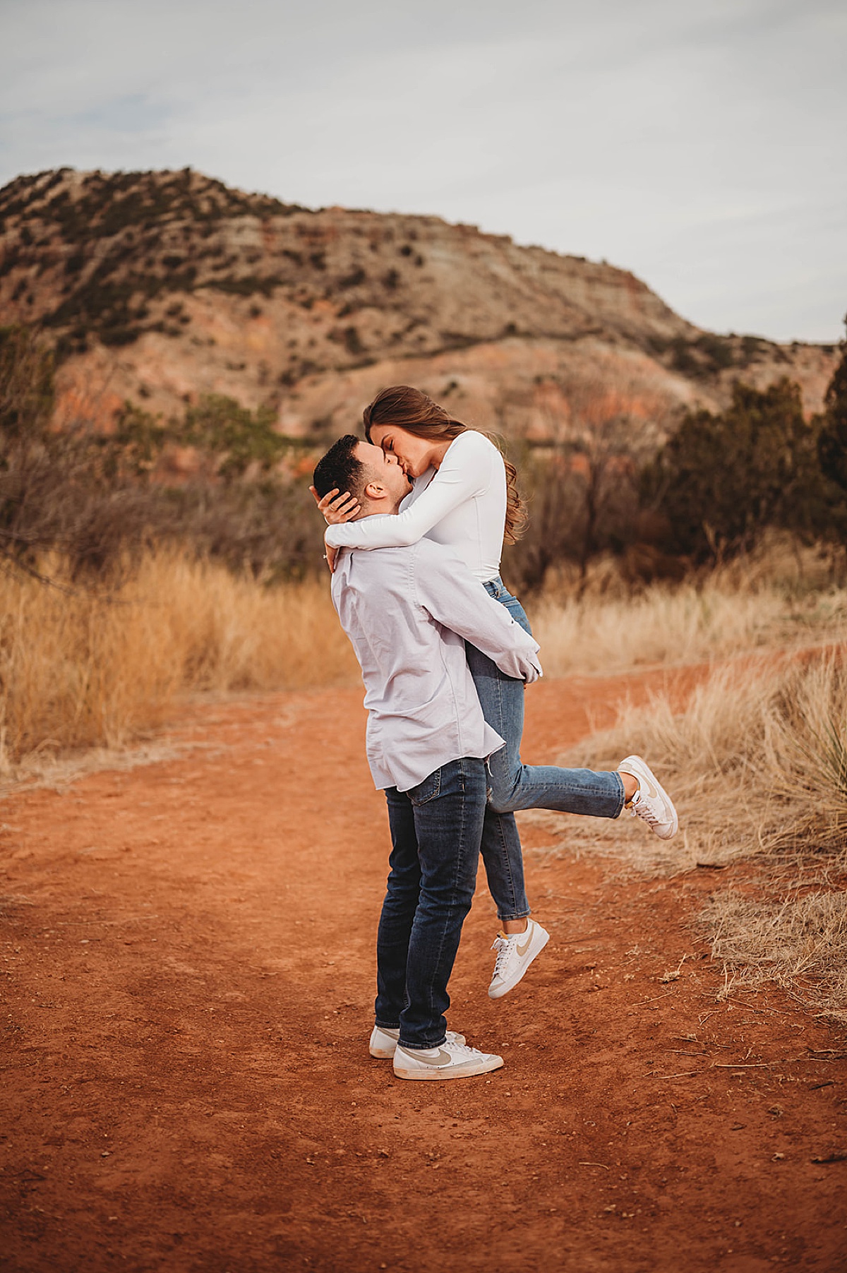 couple kisses in cute pose at palo duro canyon engagement session shot by Three Feather Photo Co
