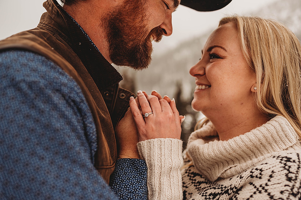 couple shows off diamond engagement ring in snowy western winter engagement shoot