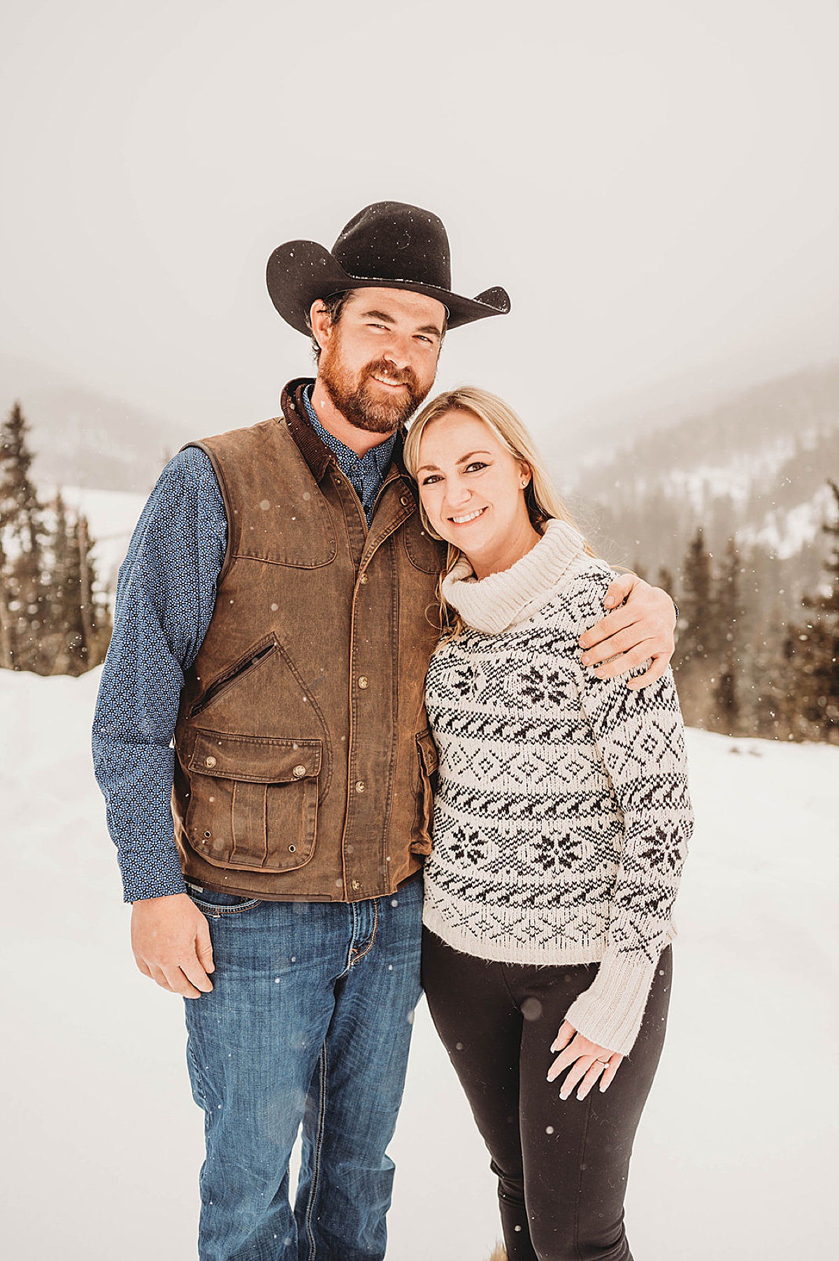 couple in cozy winter outfits pose on snowy mountain in new mexico engagement shoot by Three Feather Photo Co