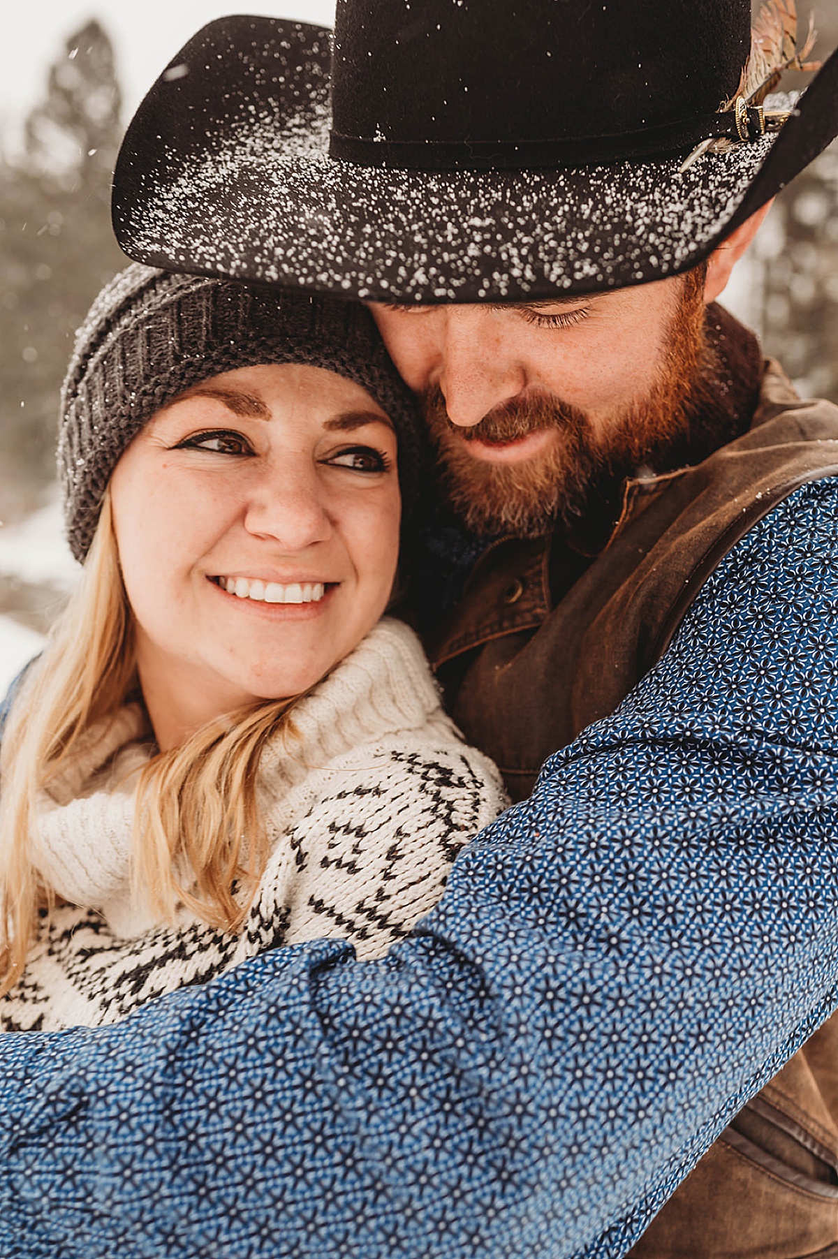 couple embrace in the falling snow during engagement shoot by Palo Duro Canyon Elopement Photographer