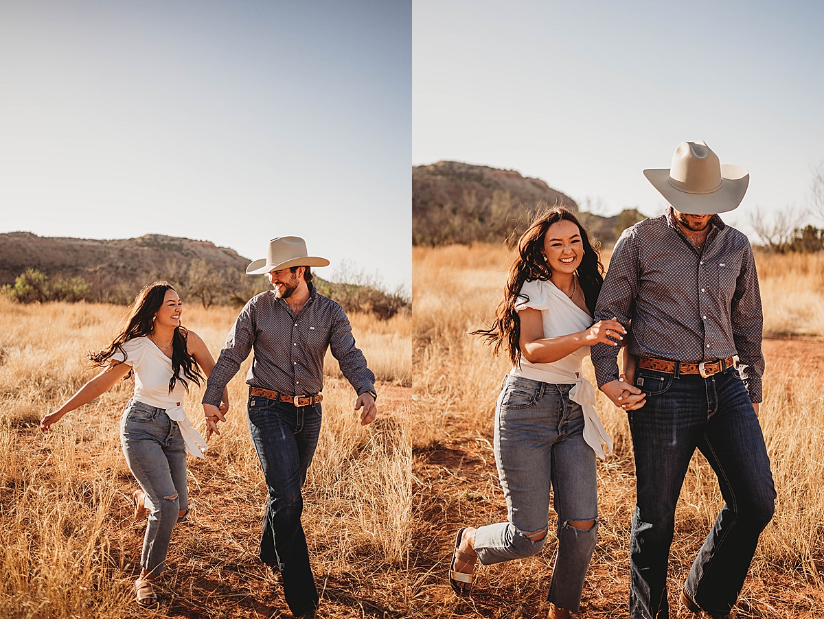 young couple laugh and walk hand in hand through grassy field during golden summer engagement shoot