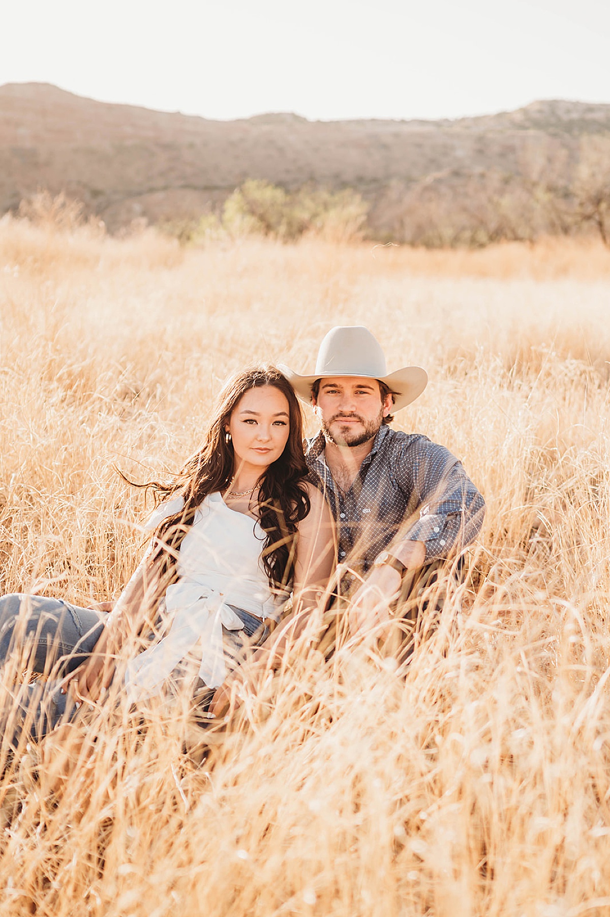 Young couple pose in boho field during shoot by Palo Duro Canyon Elopement Photographer