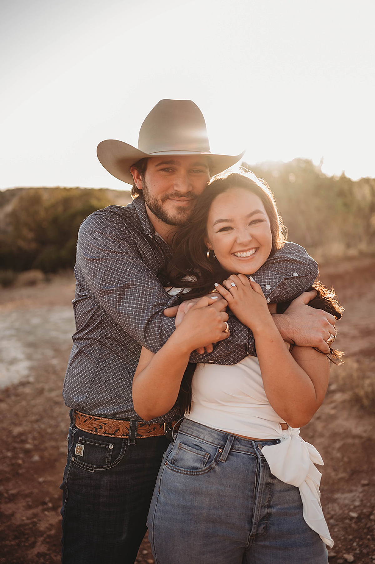 cute country couple pose for summer engagement shoot by Three Feather Photo Co