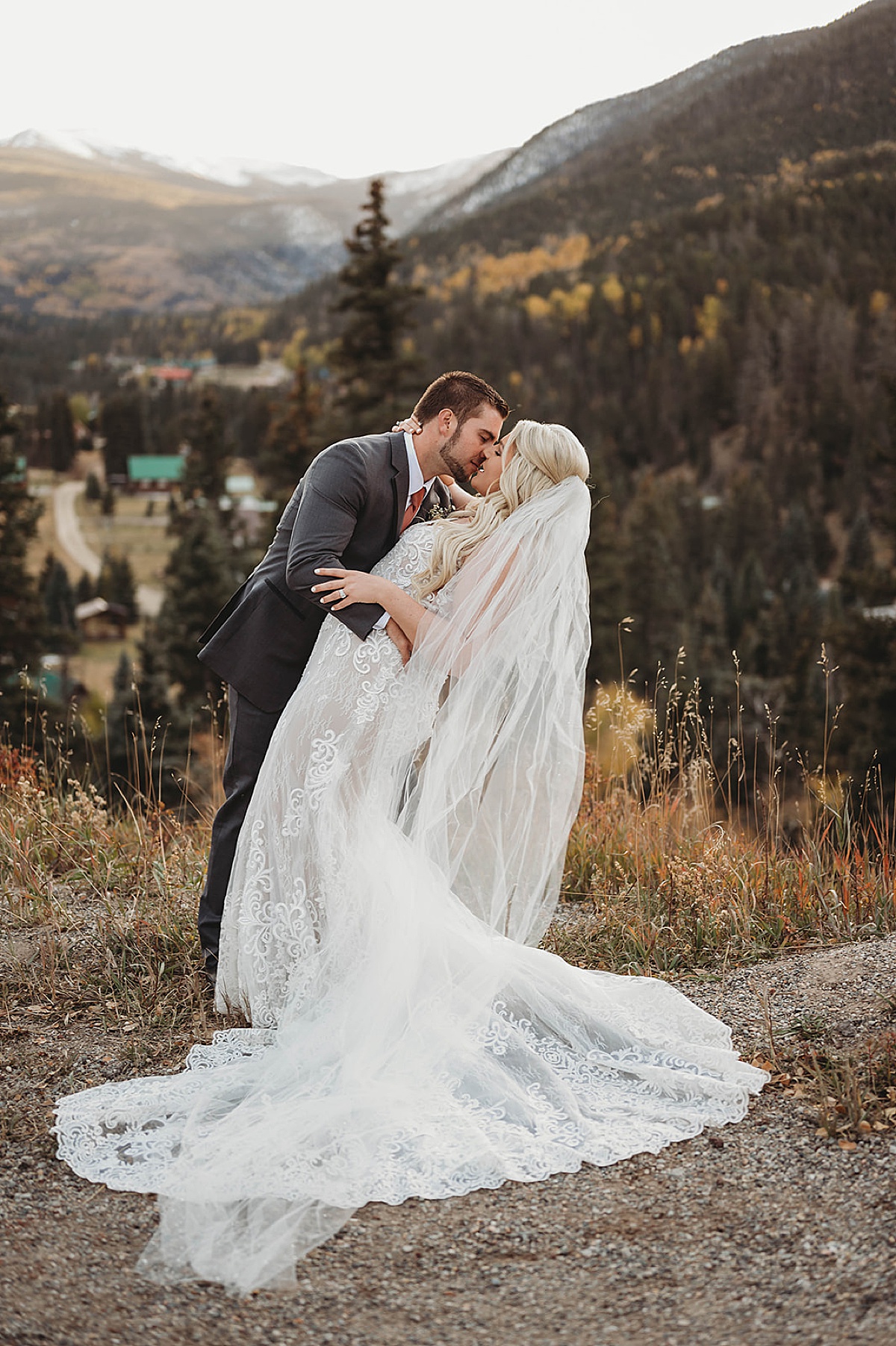 Newlywed bride and groom kiss in front of fall mountain vista after Red River Autumn Wedding
