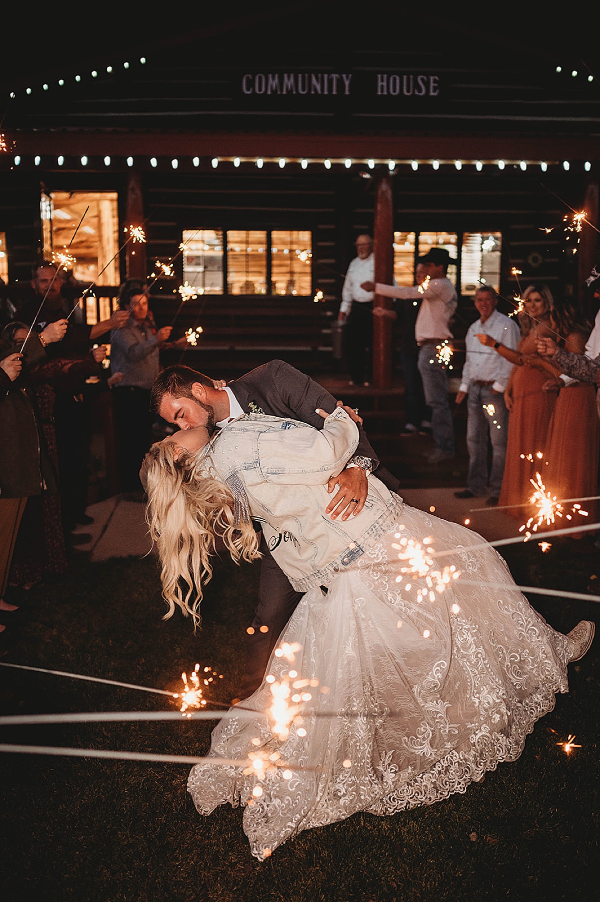 Bride and groom kiss as they leave wedding venue and guests hold sparklers. shot by palo duro canyon elopement photographer