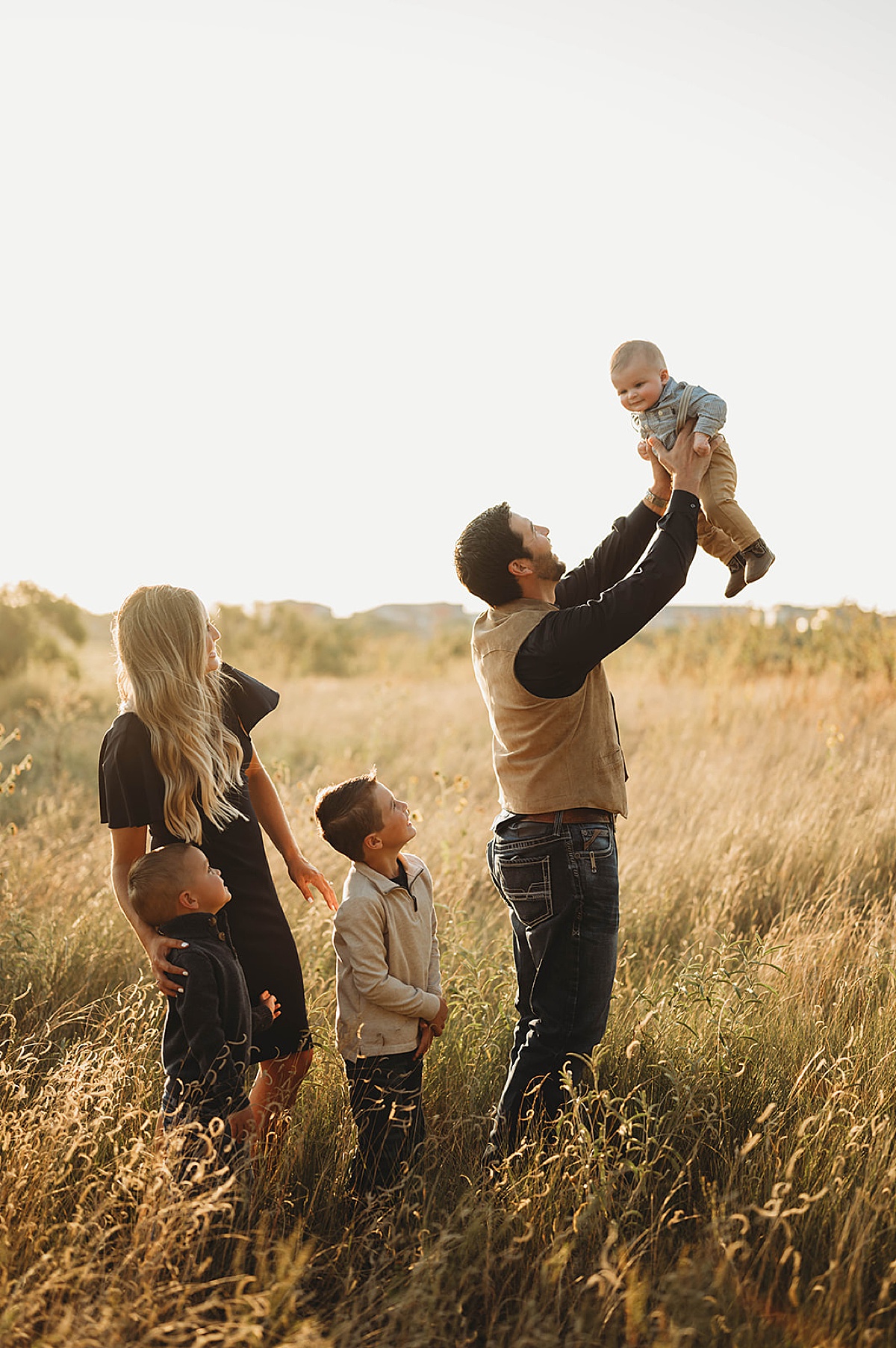 dad tosses baby in the air while mom and kids laugh during family portraits at creek house honey farm