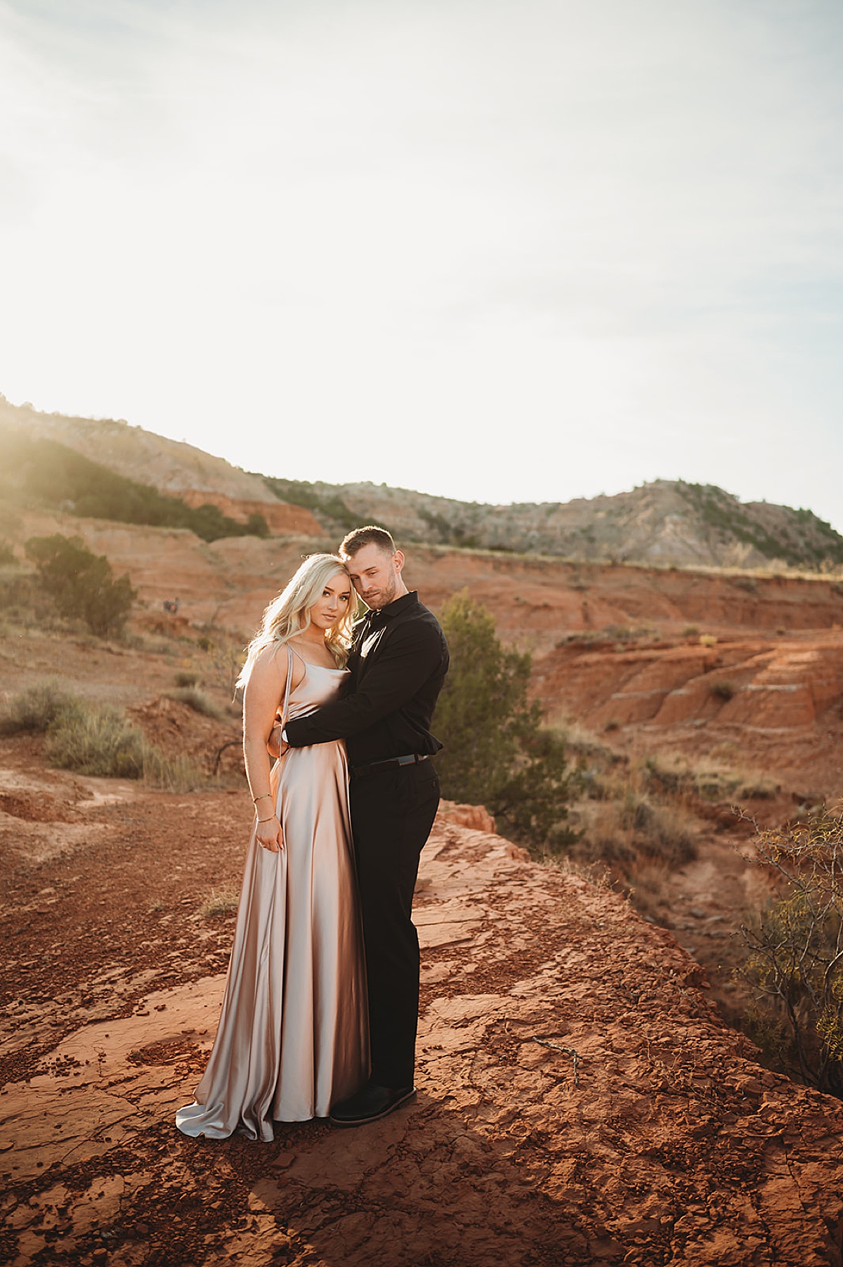 woman in satin evening gown poses with fiance during romantic canyon shoot by Three Feather Photo Co.