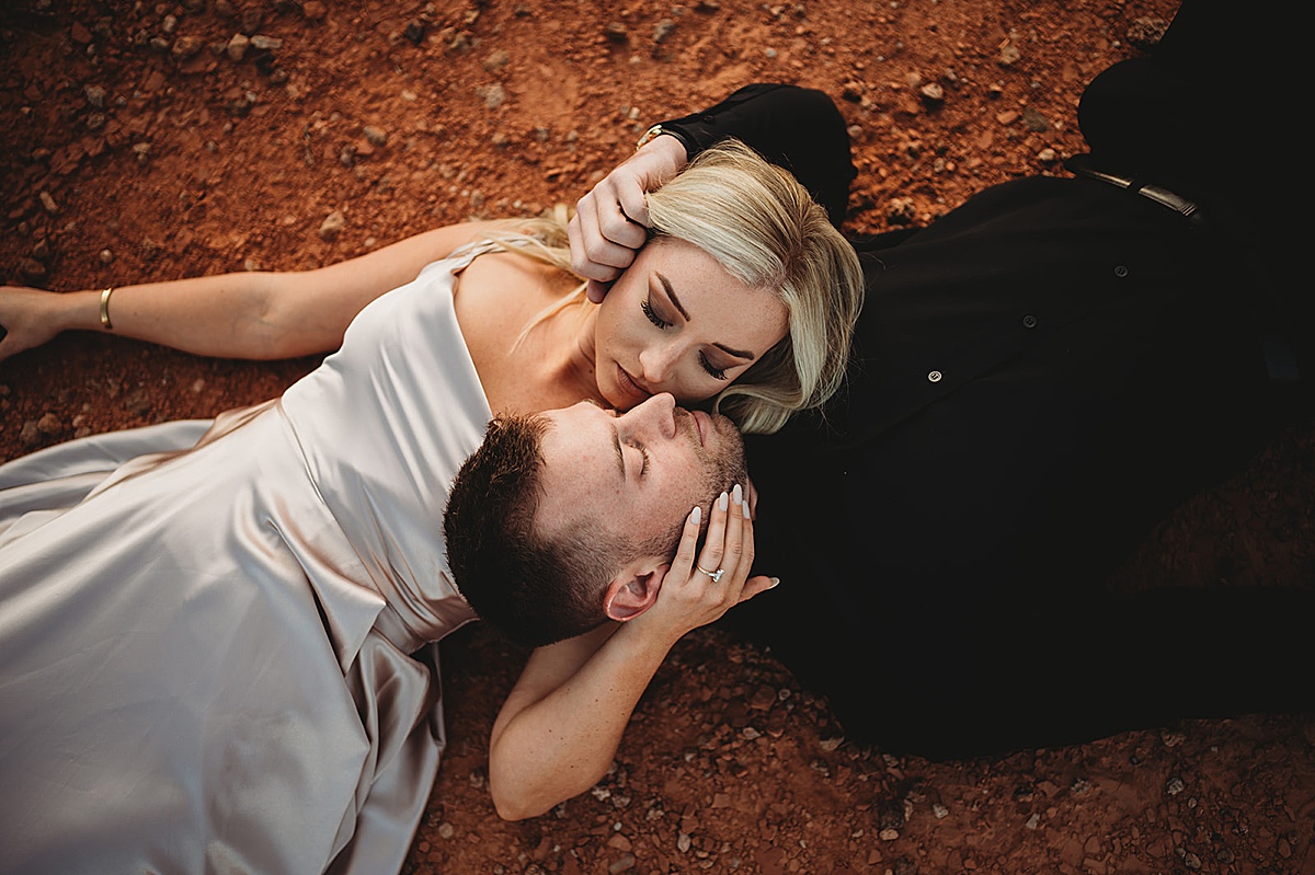couple cradle each other during romantic canyon engagement shoot by Three Feather Photo Co.