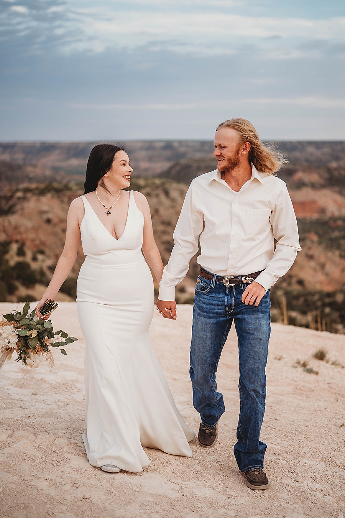 newlywed couple in minimalist western gown and white bouquet pose in canyon after sweet summer elopement