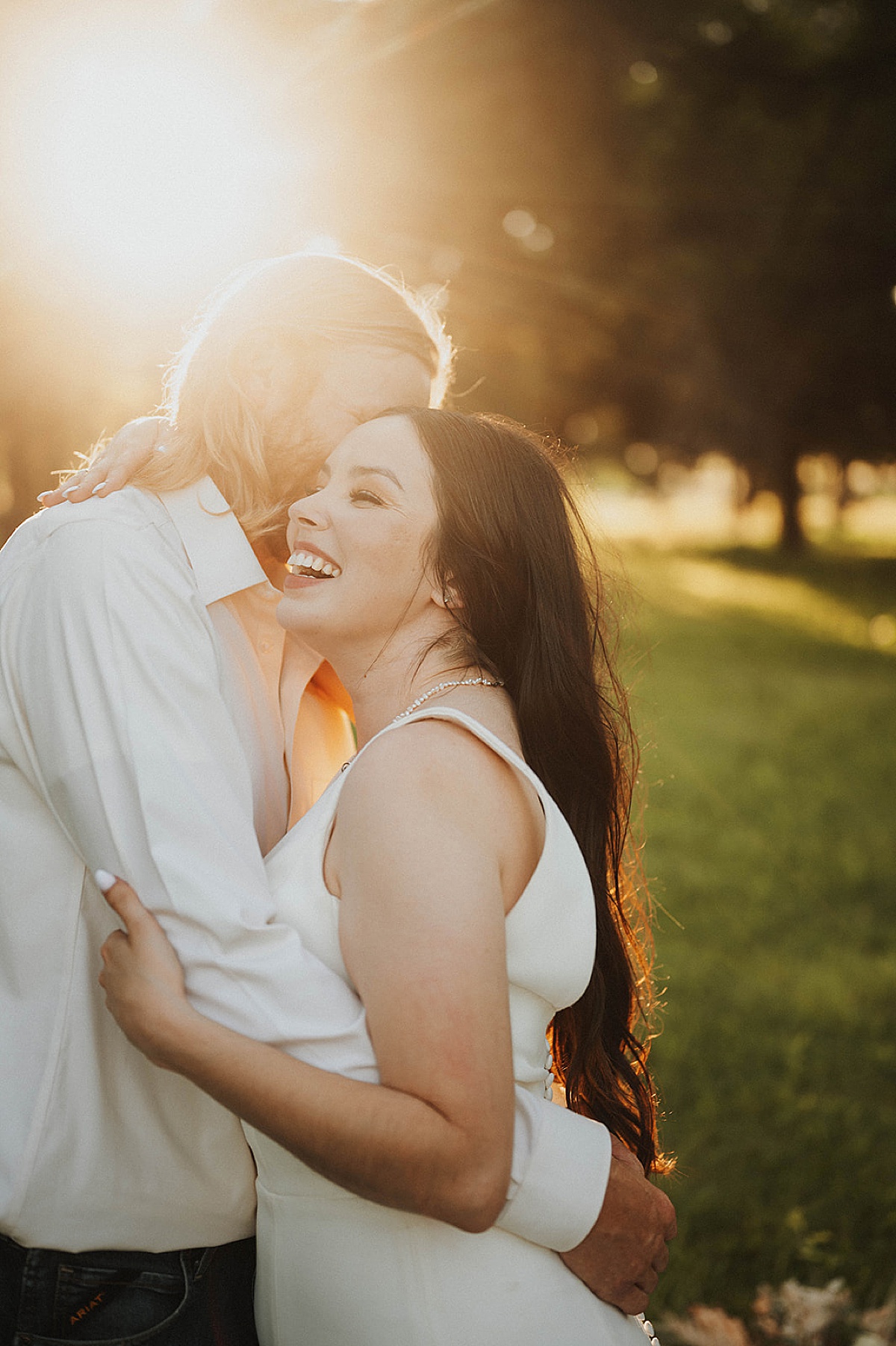 newlywed couple in white pose laughing in golden hour sunset after wedding shot by Three Feather Photo Co