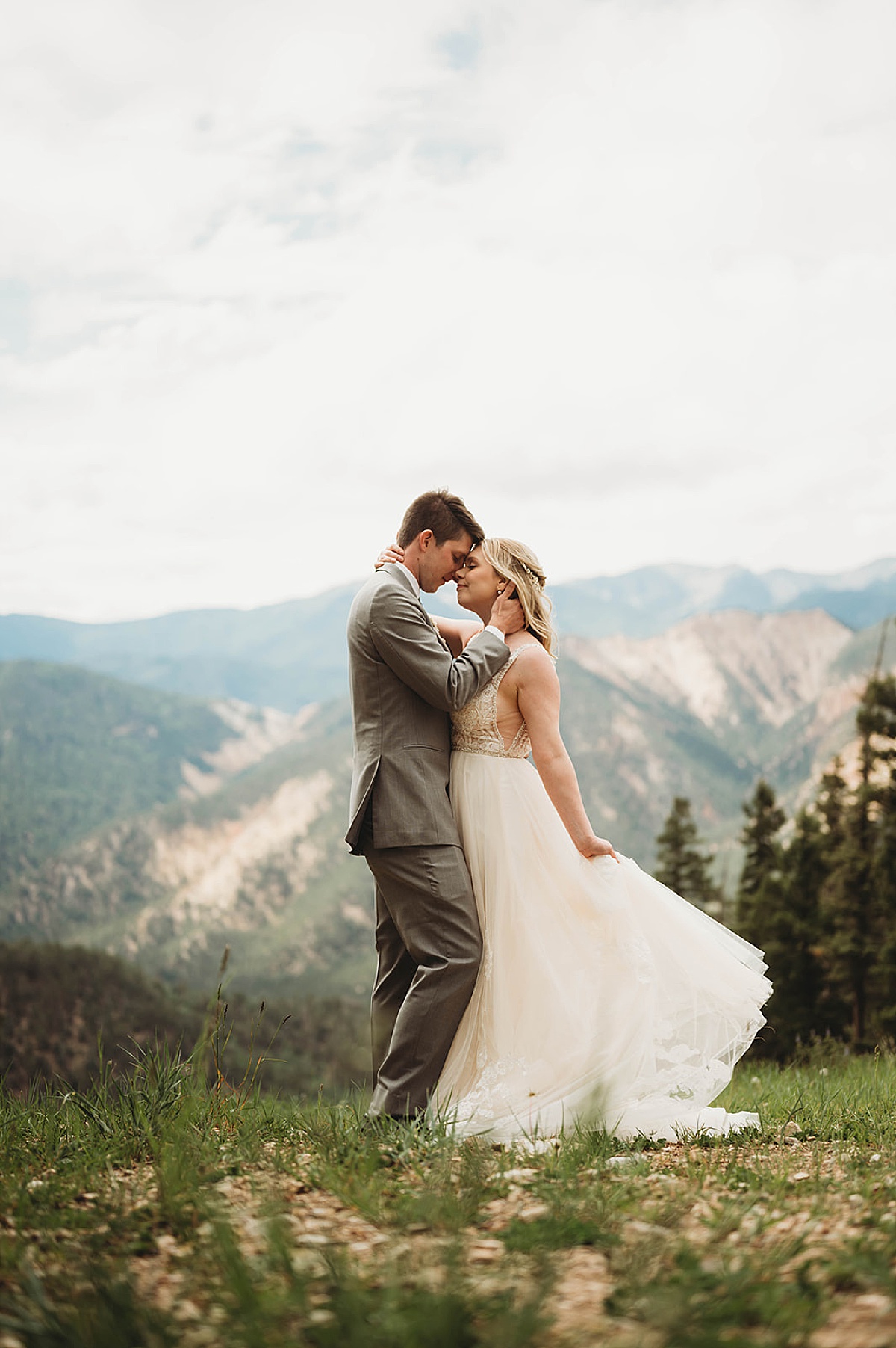 bride and groom touch foreheads in front of beautiful vista during Boho mountain top wedding