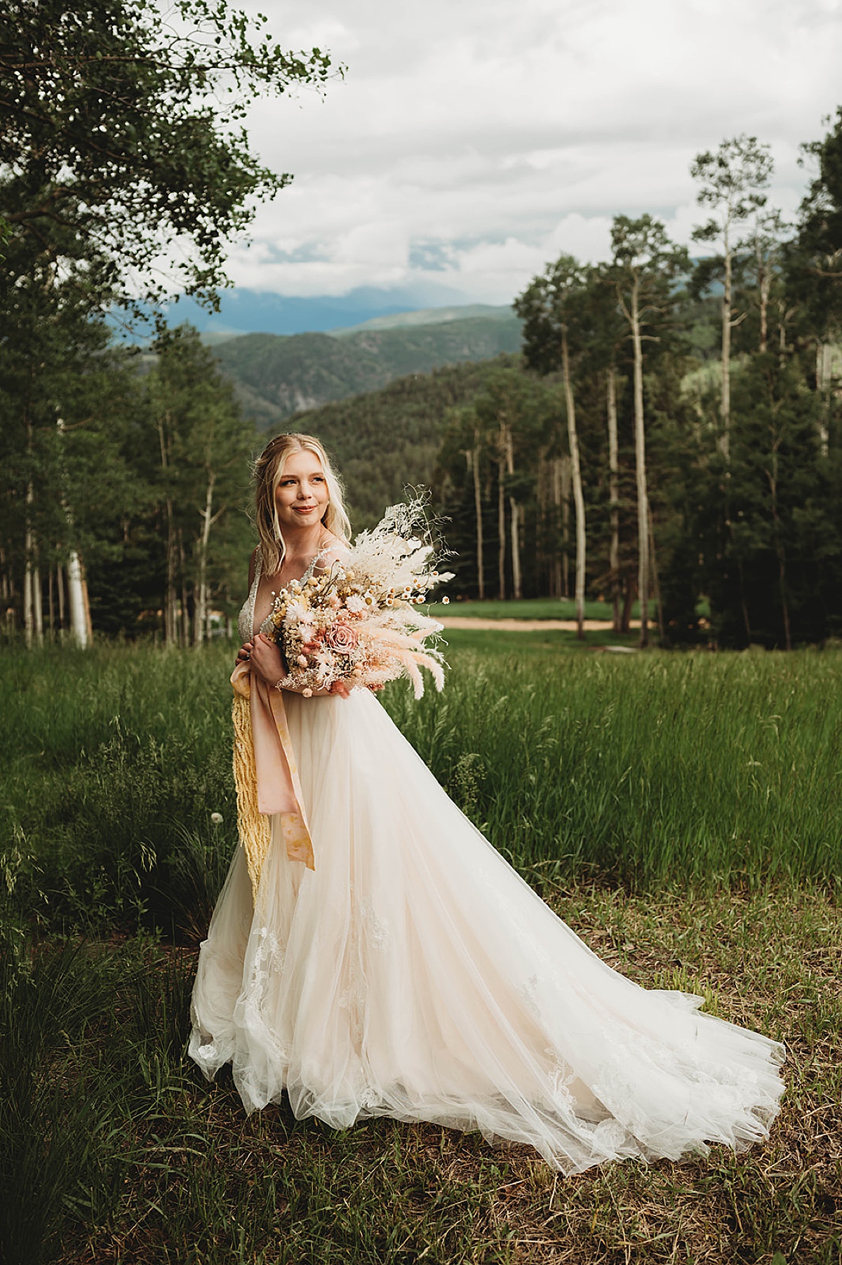 bride with dried flower bouquet poses with aspen trees before Boho mountain top wedding
