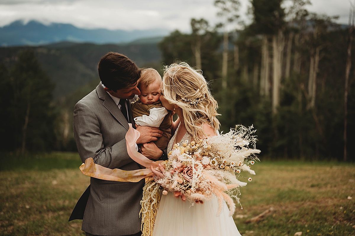 bride and groom kiss baby during mountain wedding by palo duro canyon elopement photographer