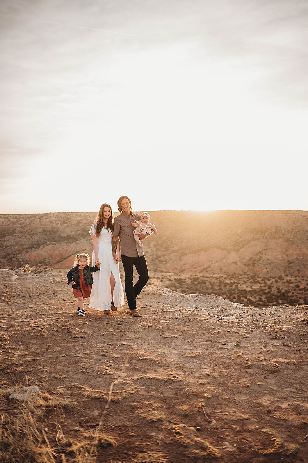 man and woman walk with baby girl and toddler during golden hour shoot by palo duro canyon elopement photographer