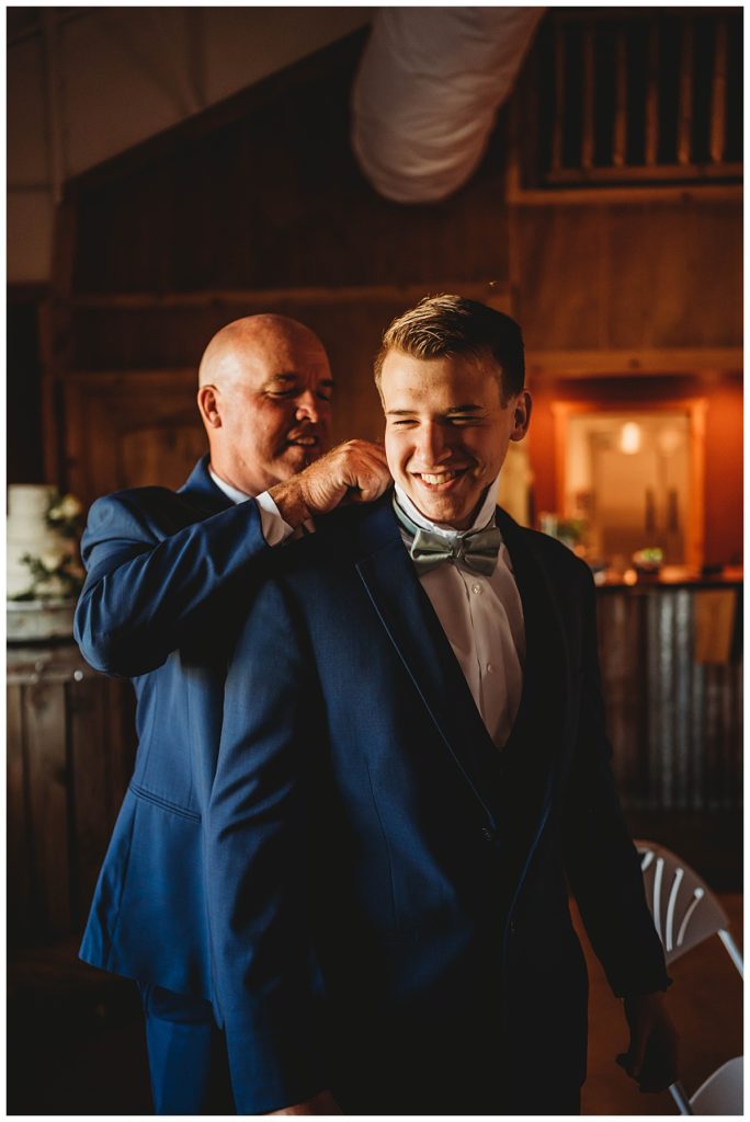 man adjusts groom's tie in Texas ranch wedding