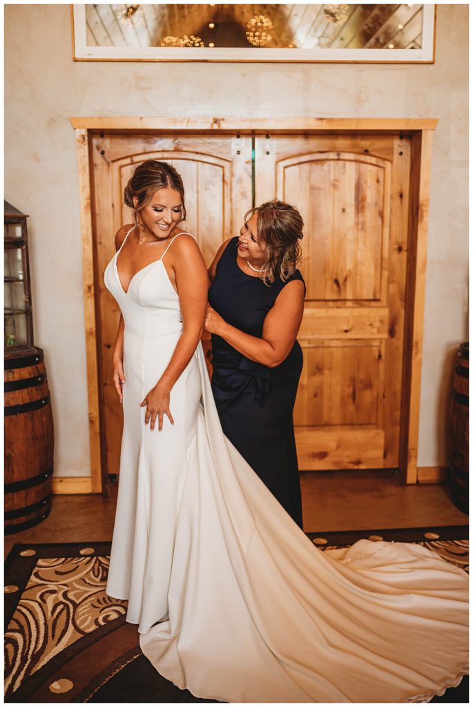 mom helps daughter with dress by Three Feather Photo Co.