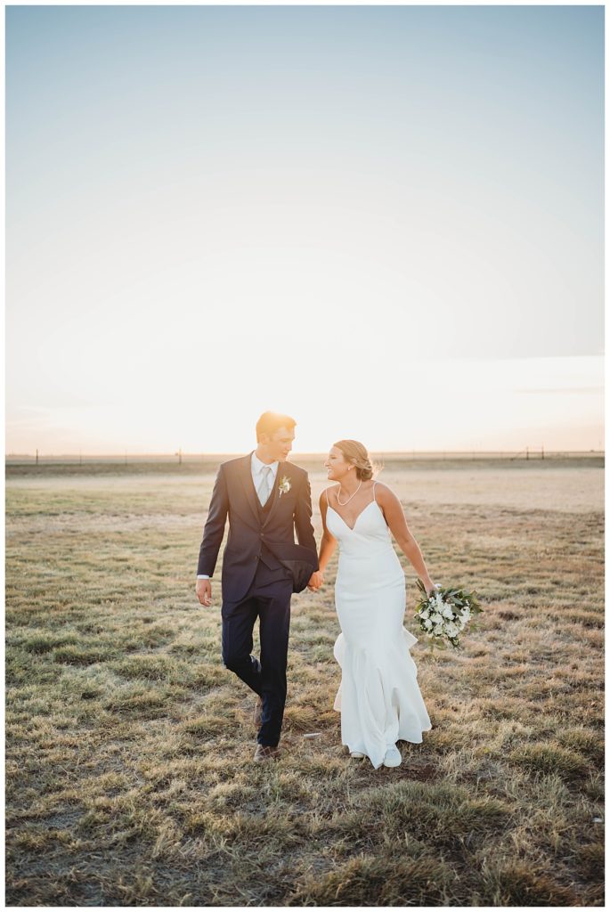man and woman walk in field by Palo Duro wedding photographer