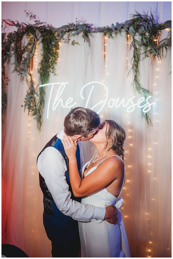 couple kisses in front of lit sign by Palo Duro photographer