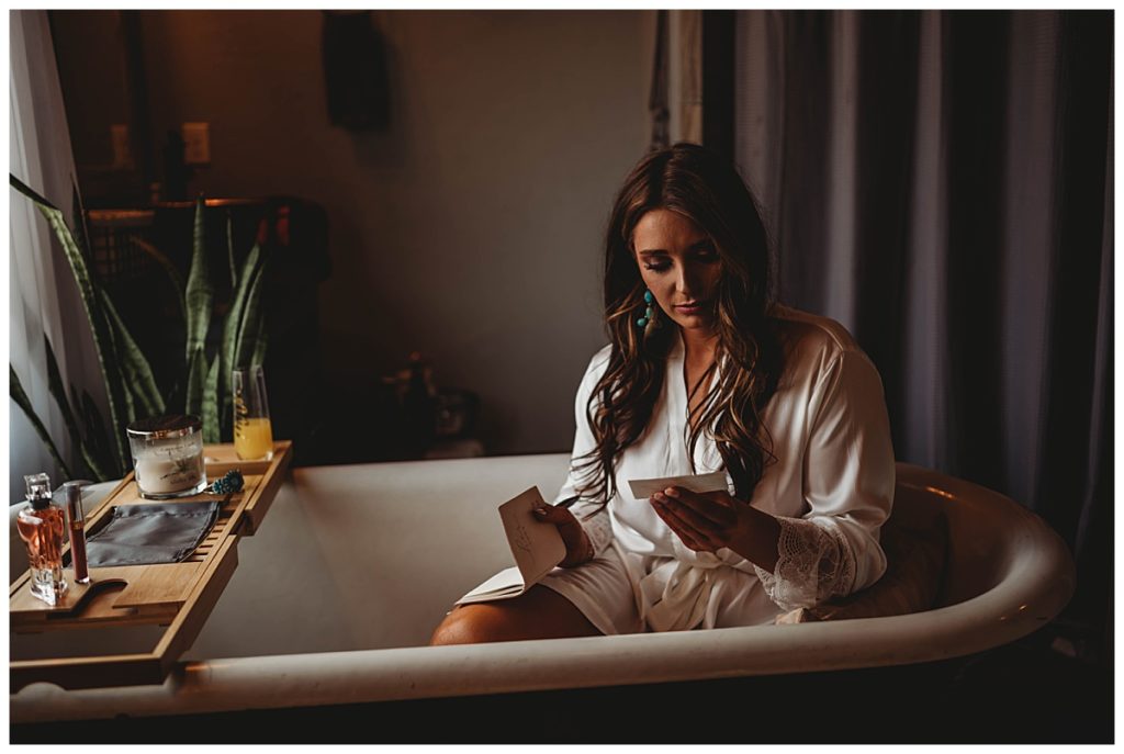 bride reading card in tub by Three Feather Photo