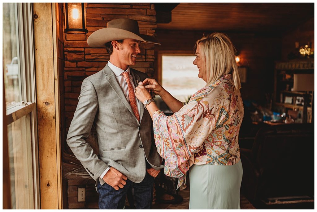 mom pinning flowers on son at Colorado cabin elopement