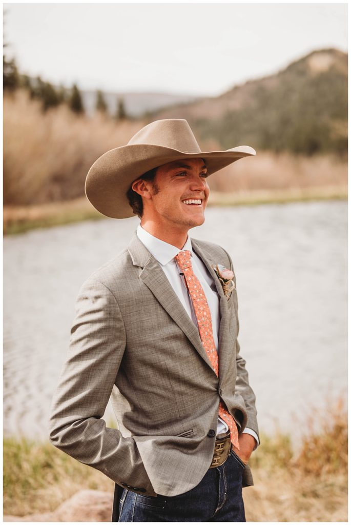man smiling in front of pond at Colorado cabin elopement
