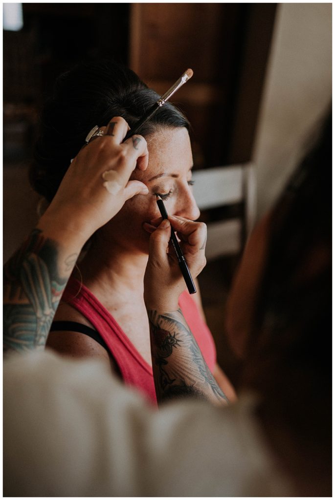 makeup artist applies makeup to woman by Three Feather Photo