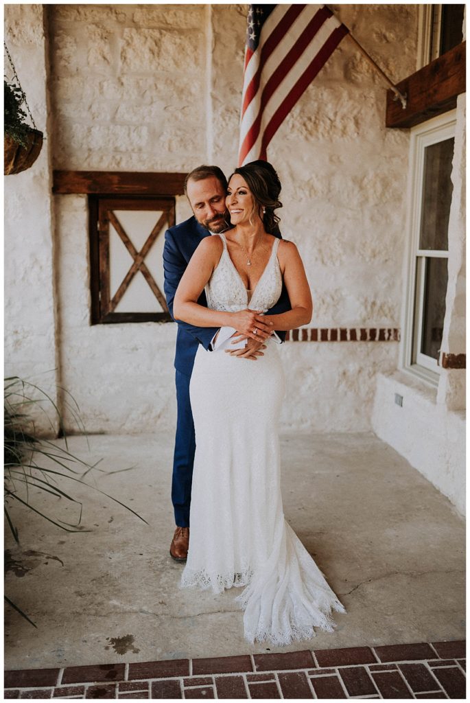 groom hugs bride from behind by Palo Duro wedding photographer
