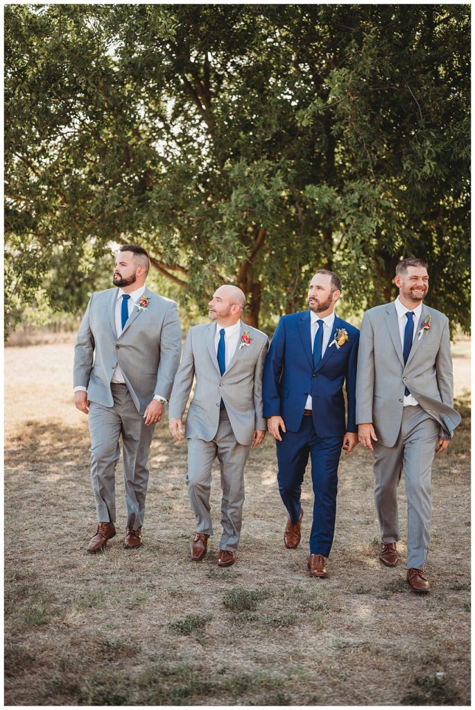 groomsmen walk toward photographer at Austin villa wedding
