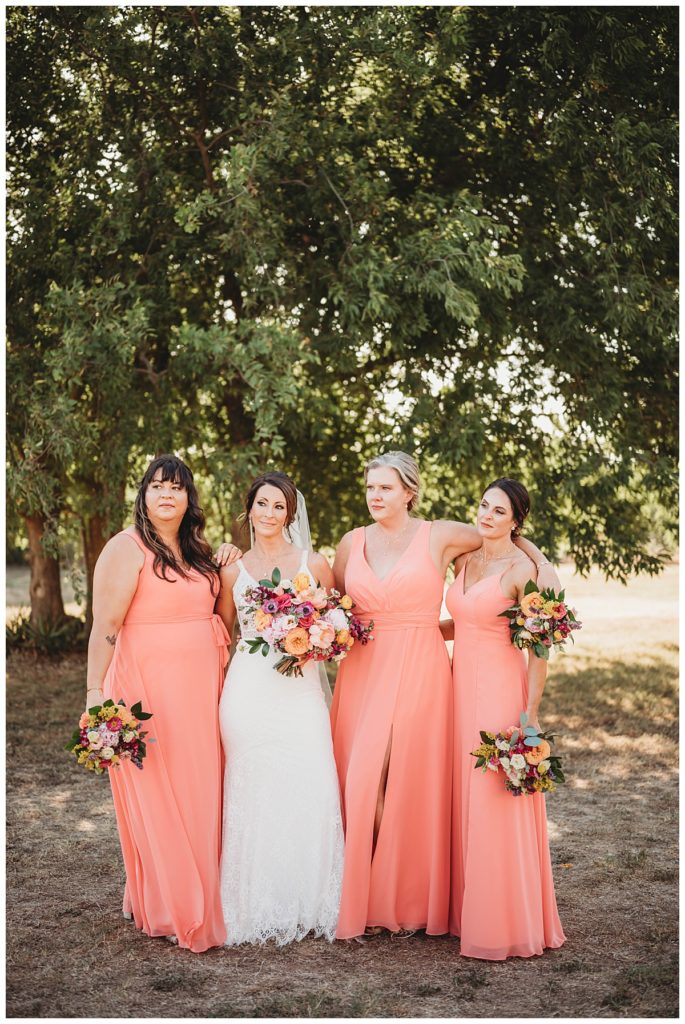 bridal party stands in grove of trees by Three Feather Photo