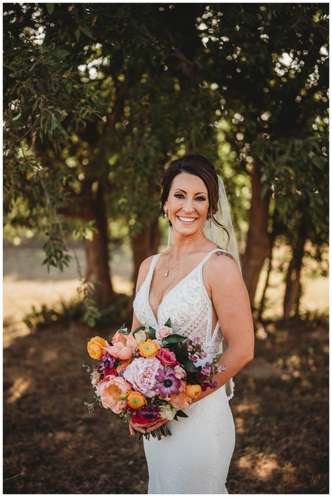 bride smiles with bouquet by Three Feather Photo