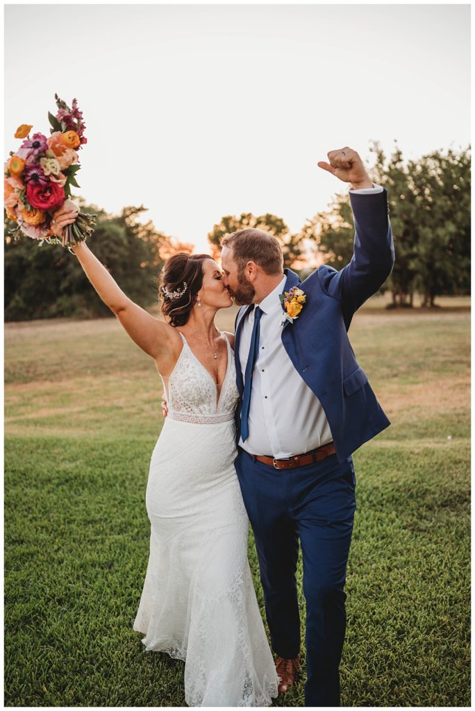 bride and groom kiss with hands in the air by Palo Duro wedding photographer