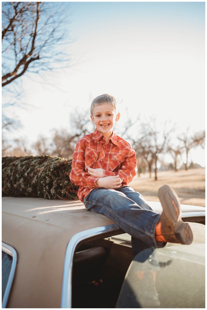 boy sits on top of car with cowboy boots at family session in Amarillo