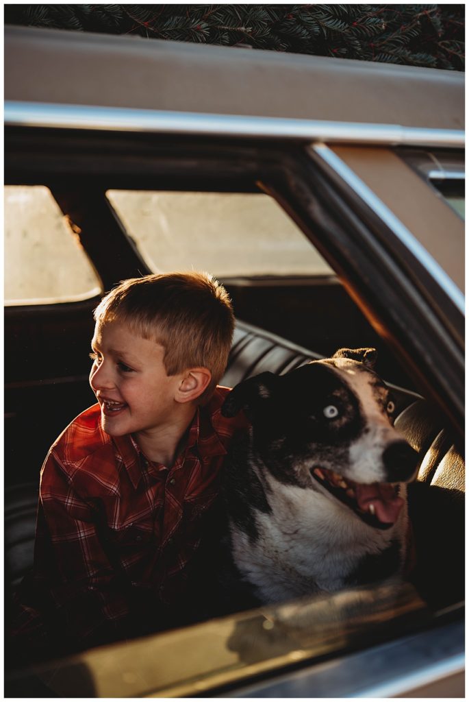 boy hugs dog in the back of a car at family session in Amarillo