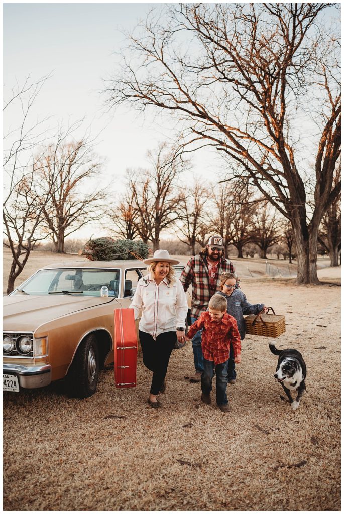 family walks together with suitcase and picnic basket by Three Feather Photo