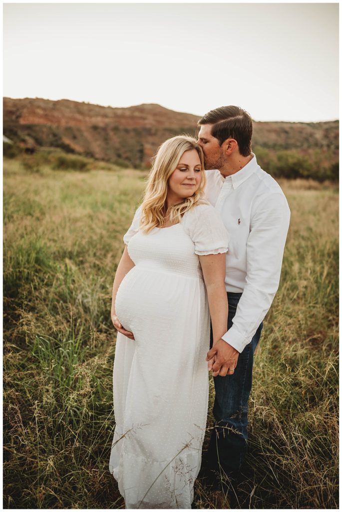 couple holds hands and leans together at canyon maternity shoot