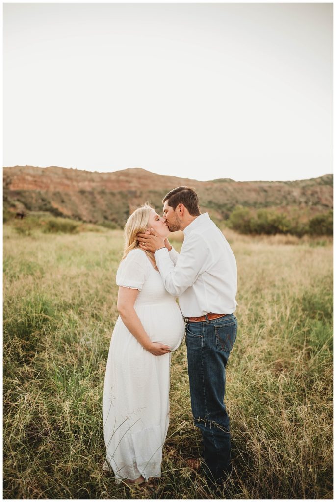 couple kisses in field by Three Feather Photo