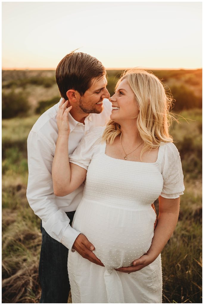 husband holds wife's pregnant stomach from behind at canyon maternity shoot