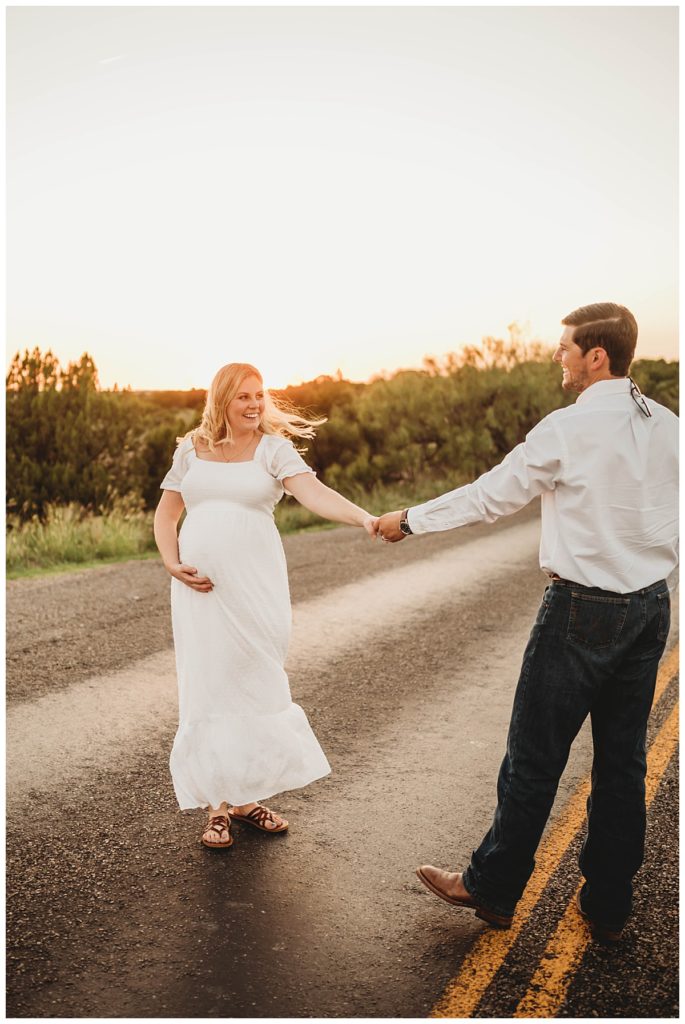 couple dances in road at canyon maternity shoot