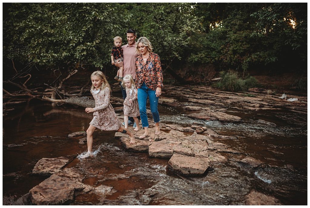 group crosses creek together for family portraits at Martin Nature Park