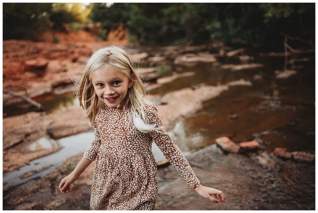 young girl stands on rocks in stream for family portraits at Martin Nature Park