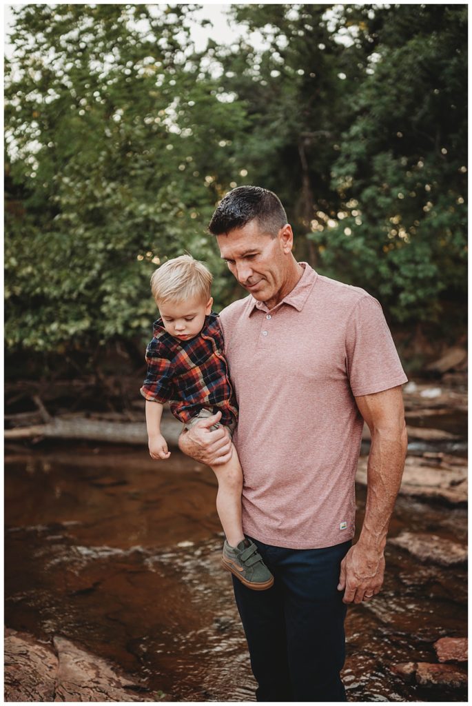 dad and son stand on rock in creek for family portraits at Martin Nature Park