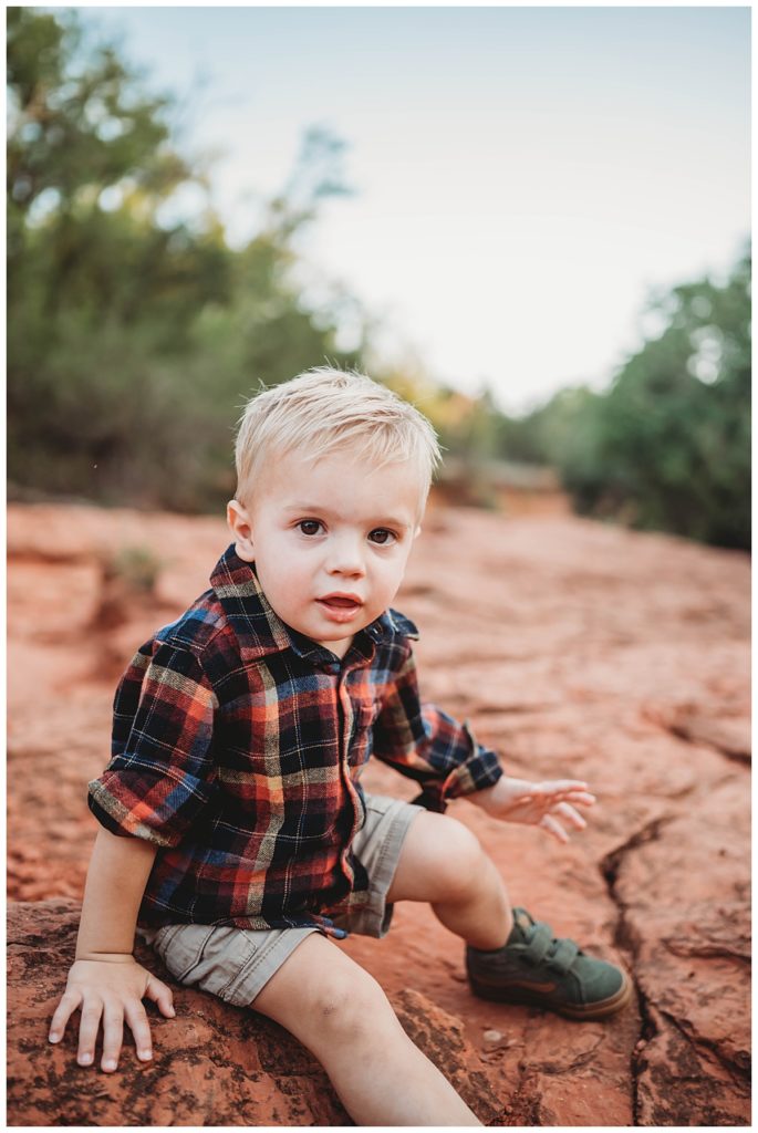 young boy sits on rock by Three Feather Photo