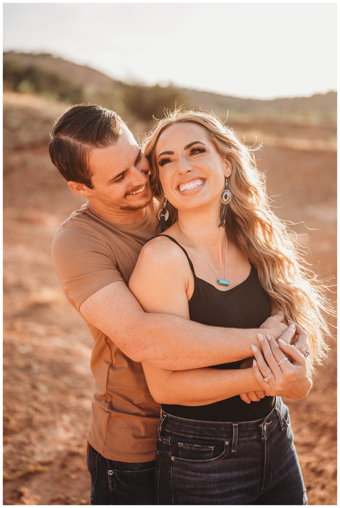 man hugs woman from behind by Amarillo Portrait Photographer