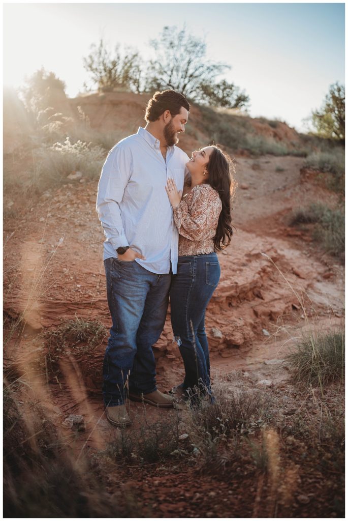 couple smiling at each other during golden hour engagement session