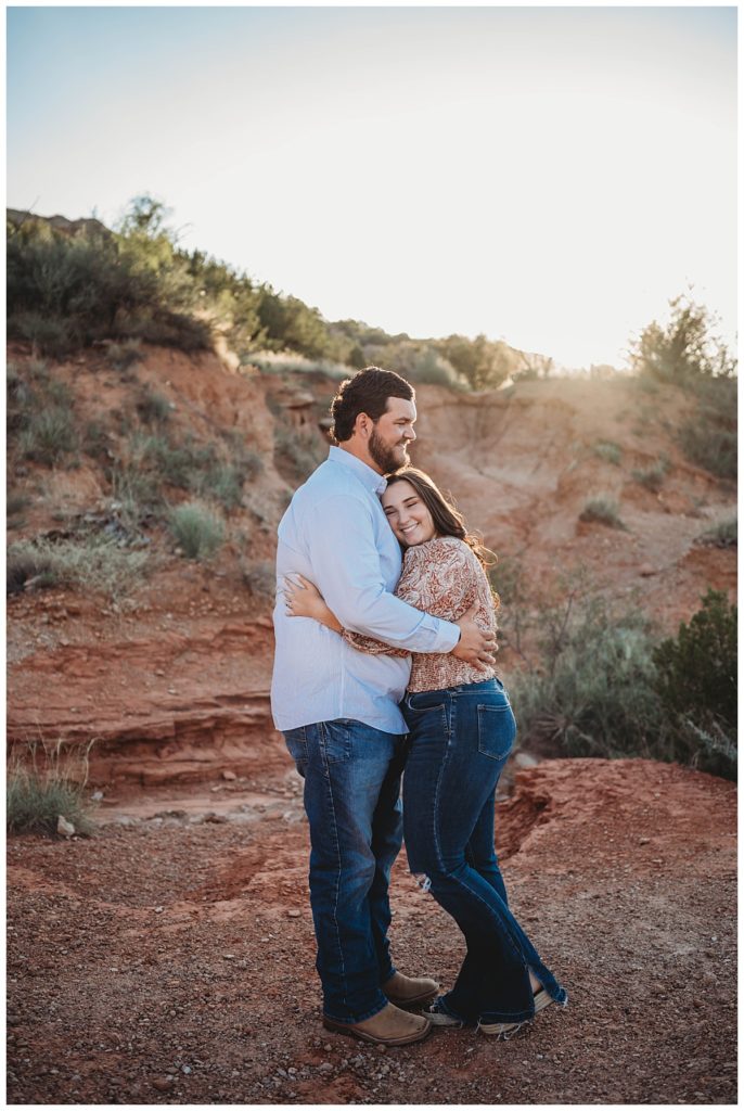 man and woman snuggling at golden hour engagement session