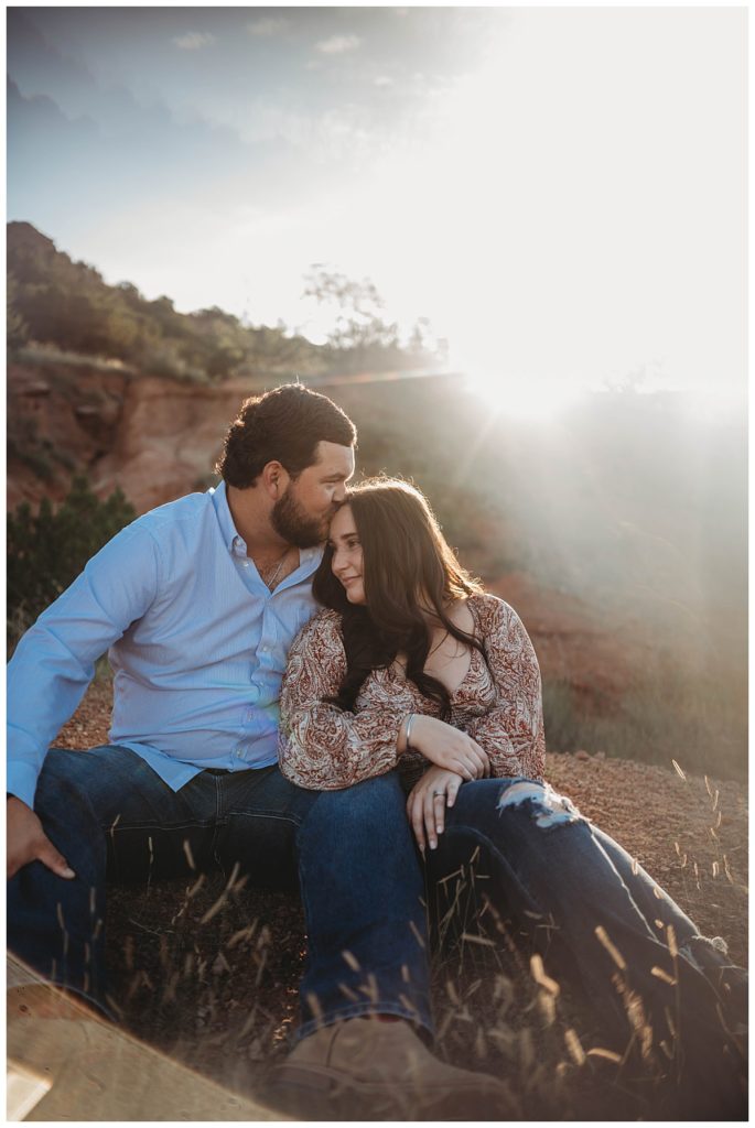 man kissing woman's forehead at golden hour engagement session